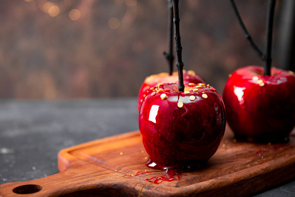  Red apples in caramel close up soft focus, an original treat for a festive Halloween table decorated with spiders and cobwebs, copy space for text. High quality photo - Photo, Image