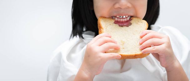 Fecha a porta. Mãos de criança segura o pão, dentes de crianças são pedaços mastigando o pão com gosto. - Foto, Imagem