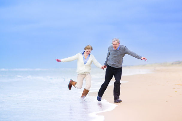 Casal de meia idade correndo em uma praia
 - Foto, Imagem