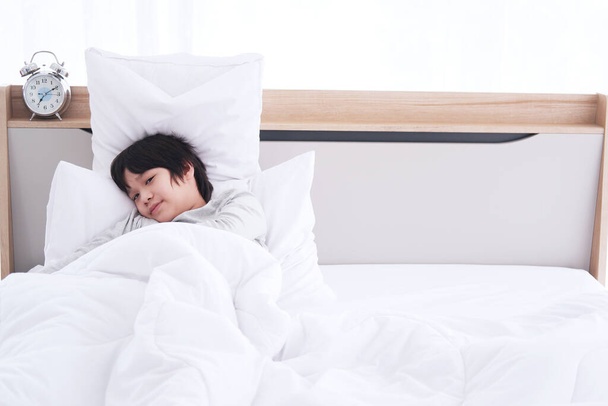 asiático chico despertar y sonrisa para feliz en la cama en la mañana en vacaciones en casa - Foto, imagen