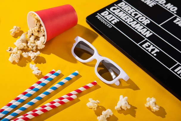 3D-Brillen, Popcorn in einer Schachtel, Klappbrett, farbige Cocktailröhre auf gelbem Hintergrund. Kino-Kokain. - Foto, Bild