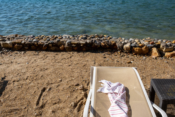 πετσέτα θαλάσσης στο ξαπλώστρα δίπλα στην παραλία - Φωτογραφία, εικόνα