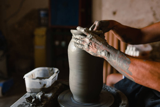 Grottaglie, Italien - August 2021: Nahaufnahme der Hände des Handwerkers bei der Herstellung eines Keramiktopfes auf der Drehbank - Foto, Bild