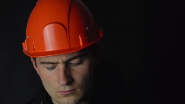 man in oranje constructie helm op zwarte achtergrond - Video