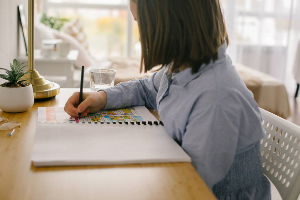 Młoda dziewczyna ucząca się w domu, pisząca notatki siedzące przy biurku. Koncepcja kształcenia w domu, koncepcja kształcenia na odległość - Zdjęcie, obraz