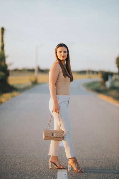 A vertical shot of a young Caucasian female model posing on a road - Foto, Imagen