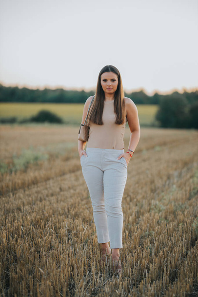 A vertical shot of a young Caucasian female model posing in a wheat field - Zdjęcie, obraz
