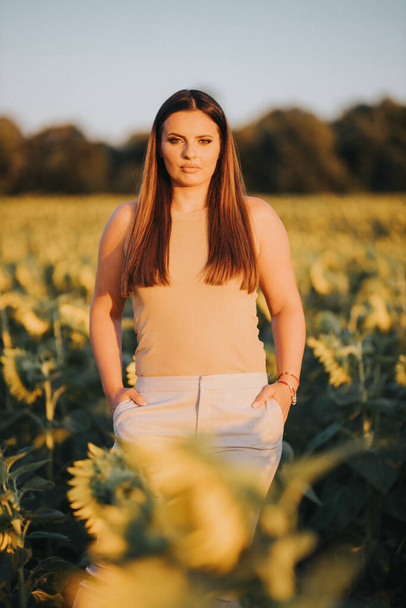 A vertical shot of a young Caucasian female model posing in a sunflower field - Foto, imagen