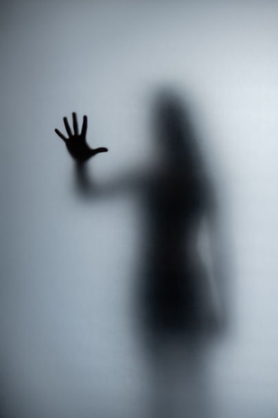 Possessed woman scratching glass with hands, creepy female silhouette, horror. Scary ghostly creature behind the glass. Halloween. Halloween image. - Photo, Image