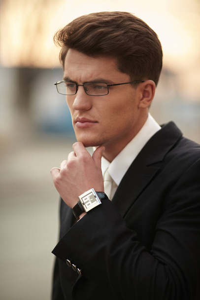 Gözlüklü yetişkin bir erkek modelin profil portresi. Siyah takım elbiseli, beyaz kravatlı ve gömlekli bir iş adamı.. - Fotoğraf, Görsel