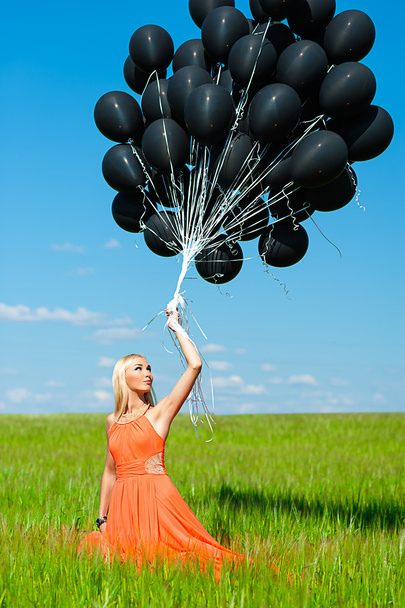 Woman looking up at the black balloons - Zdjęcie, obraz