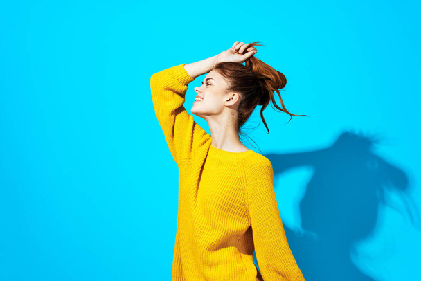 женщина в желтом свитере стиль жизни обрезанный вид синий фон - Фото, изображение