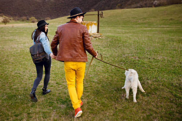 Una joven pareja pasa tiempo fuera con su perro cascarrabias. Concepto romántico estilo de vida. - Foto, Imagen