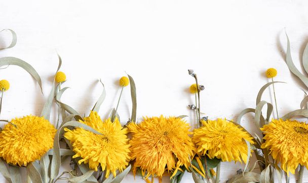 Fondo plano blanco festivo con girasoles y flores de craspedia, espacio para copiar. - Foto, imagen