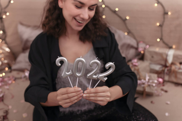 Молодая женщина держит свечи в виде цифр 2022, новый год праздник концепции. - Фото, изображение