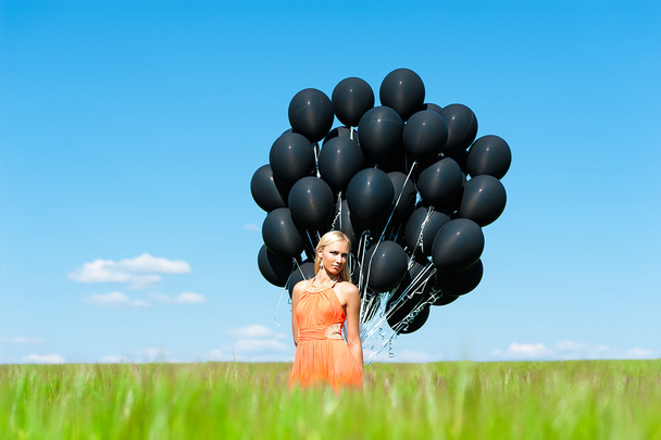 フィールド上の黒の風船を持つ女性 - 写真・画像