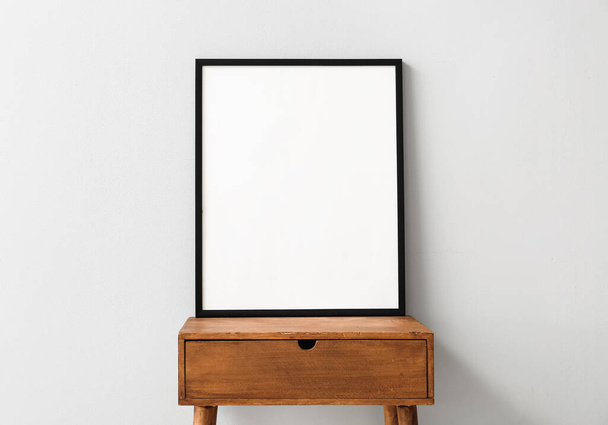 Marco del cartel en blanco en la mesa de madera cerca de la pared de luz - Foto, Imagen