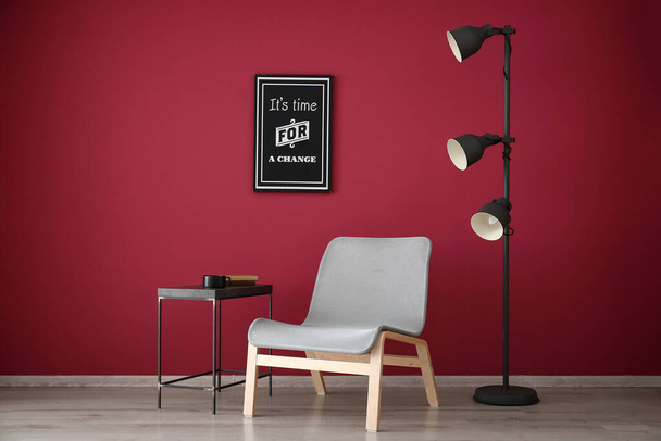 Стильний дизайн вітальні з сучасним кріслом біля кольорової стіни
 - Фото, зображення