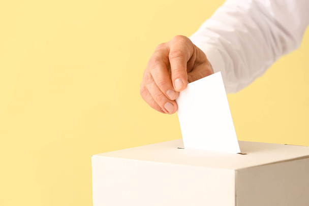 Voting man near ballot box on color background - Foto, imagen