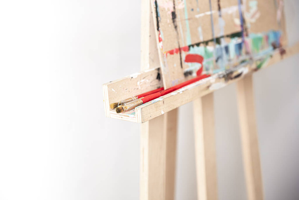 Brushes for painting on a wooden stand for an easel, blurred background, copy space. - Foto, Imagen