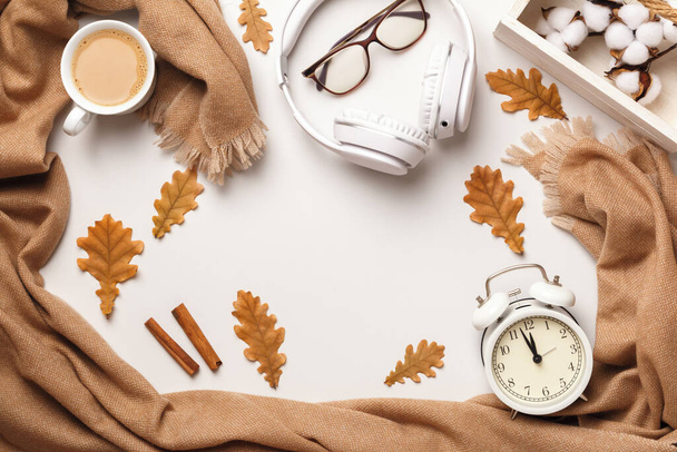 Autumn concept. Beige cashmere scarf, glasses headphones a cup of coffee with autumn leaves on a white background. Flat lay top view - Фото, зображення