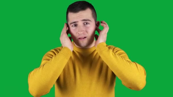 man die zijn oren bedekt met zijn handen op een groen scherm - Video