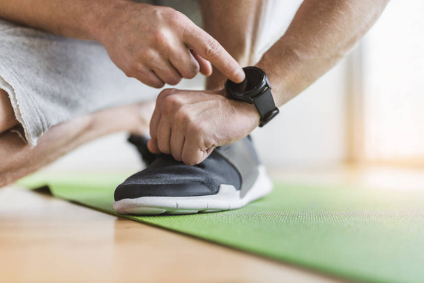 Handsome young man working out at home with a smart watch - Foto, Bild