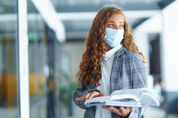 Portrait of young business woman in protective face mask at office. Female Entrepreneur. People, business, freelance, work concept. COVID - 19. - Photo, Image