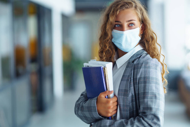 Portrait of young business woman in protective face mask at office. Female Entrepreneur. People, business, freelance, work concept. COVID - 19. - Foto, Imagen