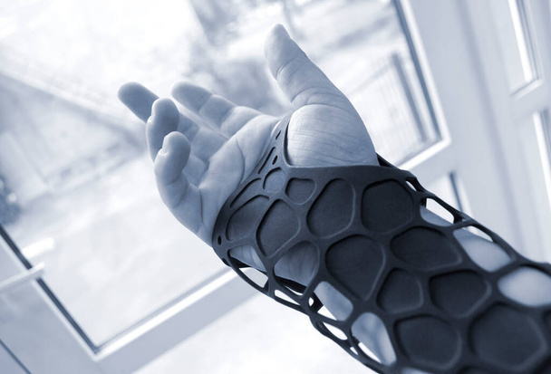 Eldeki 3D yazıcıya basılmış siyah ortopedik plastik protez.. - Fotoğraf, Görsel