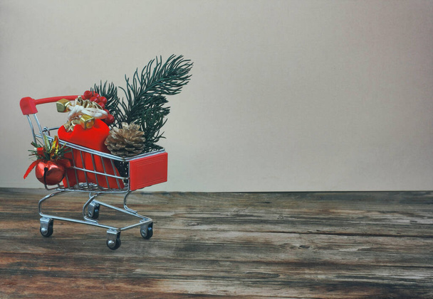 christmas, new year background, supermarket trolley, red bag with gift, on wooden surface - Φωτογραφία, εικόνα