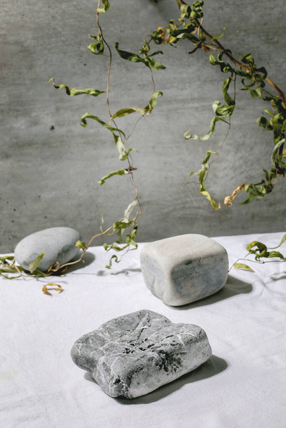 Abstract natural scene with geometrical stones as podium or pedestals for products presentation or exhibitions on white textile with branch decor. Scene to show any products for advertising. - Foto, afbeelding