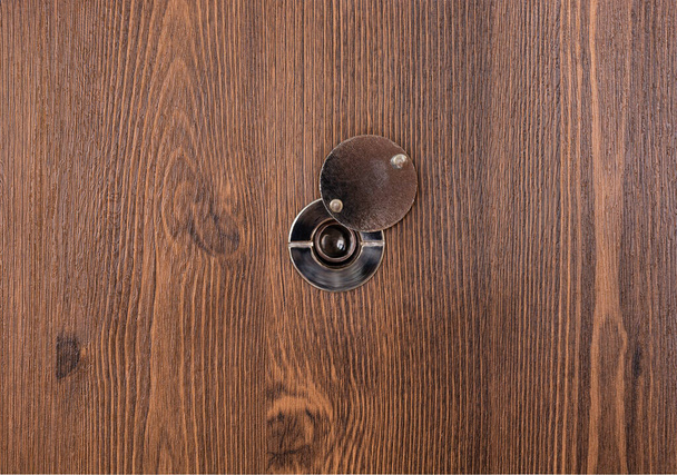 opening door peephole with a lens on a dark wooden texture. copy space. - Photo, Image