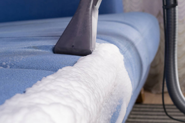 the vacuum cleaner collects foam for dry cleaning of upholstered furniture side view - Foto, Imagen