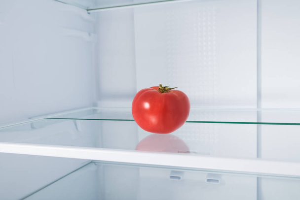 red tomato on a glass shelf in the refrigerator - Foto, afbeelding