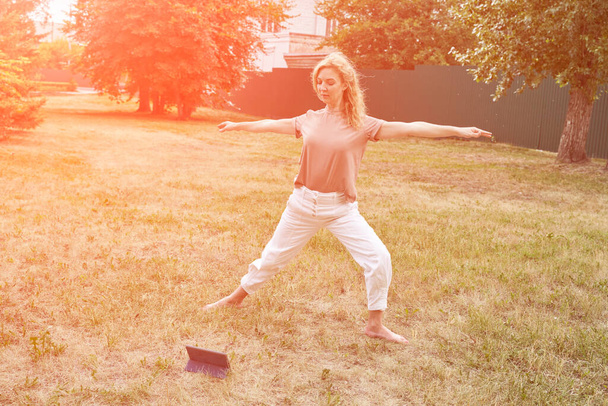 Mujer en el patio trasero. Escuela de yoga en línea. Vacaciones activas. Pelo rubio. Gente - Foto, Imagen