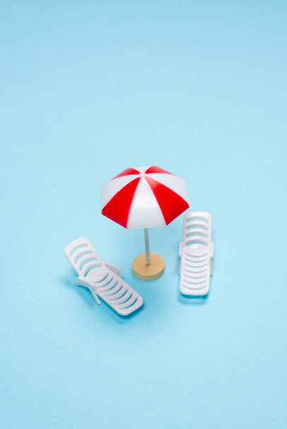 Travel concept. Sun lounger, red umbrella on a blue background. Copy space.  - Фото, зображення