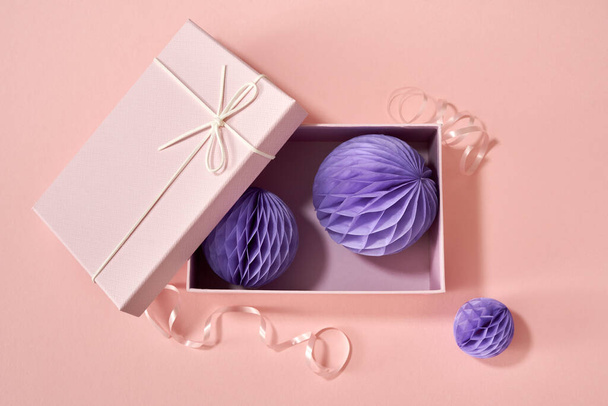 A gift box with pleated Christmas ornaments on pastel pink background, top view - Foto, Imagen