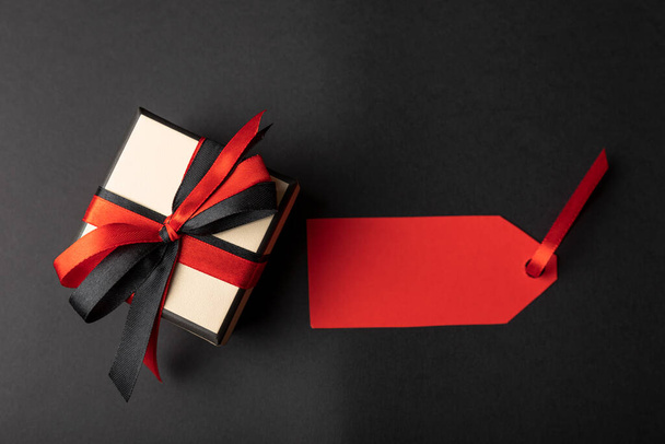 Geschenkbox mit Preisschild auf schwarzem Hintergrund mit Kopierraum. - Foto, Bild