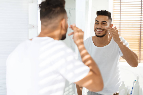 Skincare For Men. Handsome Middle Eastern Guy Applying Moisturising Cream On Face - Photo, Image