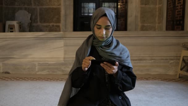 Chica musulmana leyendo quran con teléfono móvil en masjid - Metraje, vídeo