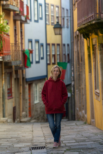 A woman in a hoodie walks through an old Portuguese town. - Photo, Image
