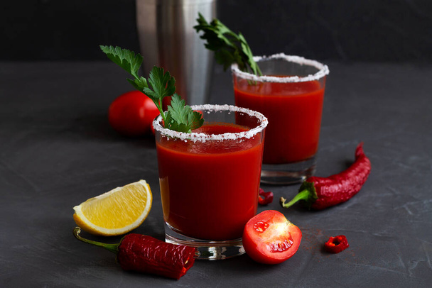 Fresh Tomato juice with pepper, spices, salt and yellow lemon in glass with copy space. Bloody Mary cocktail. Alcoholic drink with vodka, vampiro cocktail and ingredients on the black background. - Photo, Image
