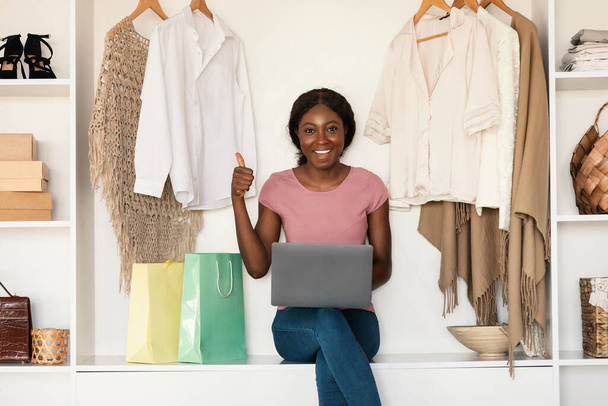 Afrikaanse Amerikaanse vrouw winkelen Online met behulp van laptop Gesturing Thumbs-Up Binnenshuis - Foto, afbeelding