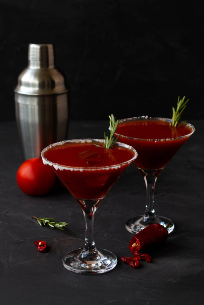 Bloody Mary cocktail. Alcoholic drink with vodka and tomato juice in a glass isolated on a black background. vampiro cocktail with pepper on a busy bar top. copy space. vertical - Photo, Image