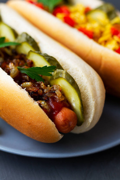 hot dog mustárral közelkép dán hot dog uborkával, sült hagymával, szósszal és ketchup egy fa tálcán egy étteremben. Hot dog a szürke tányéron. Gyorséttermi koncepció másolási hellyel. függőleges - Fotó, kép