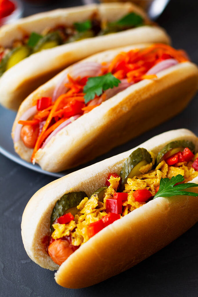 Χοτ-ντογκ στο γκρι πιάτο. close-up Hot dog με τουρσί, τηγανητά κρεμμύδια, σάλτσα και κέτσαπ σε ξύλινο δίσκο σε εστιατόριο. Fast food έννοια με αντίγραφο χώρο. κατακόρυφος - Φωτογραφία, εικόνα