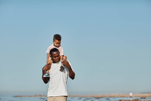 Junger Vater trägt Sohn bei blauem Himmel - Foto, Bild
