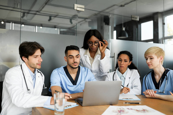 Профессиональная команда врачей смотрит на экран ноутбука - Фото, изображение