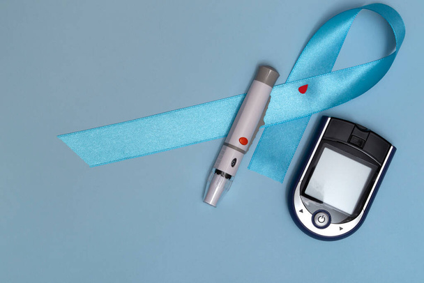世界糖尿病デーのための概念のトップビューを閉じます14 11月.青い背景に血滴と光子の付いた青いテープ. - 写真・画像